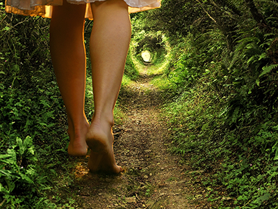 A woman walks down a woodland path